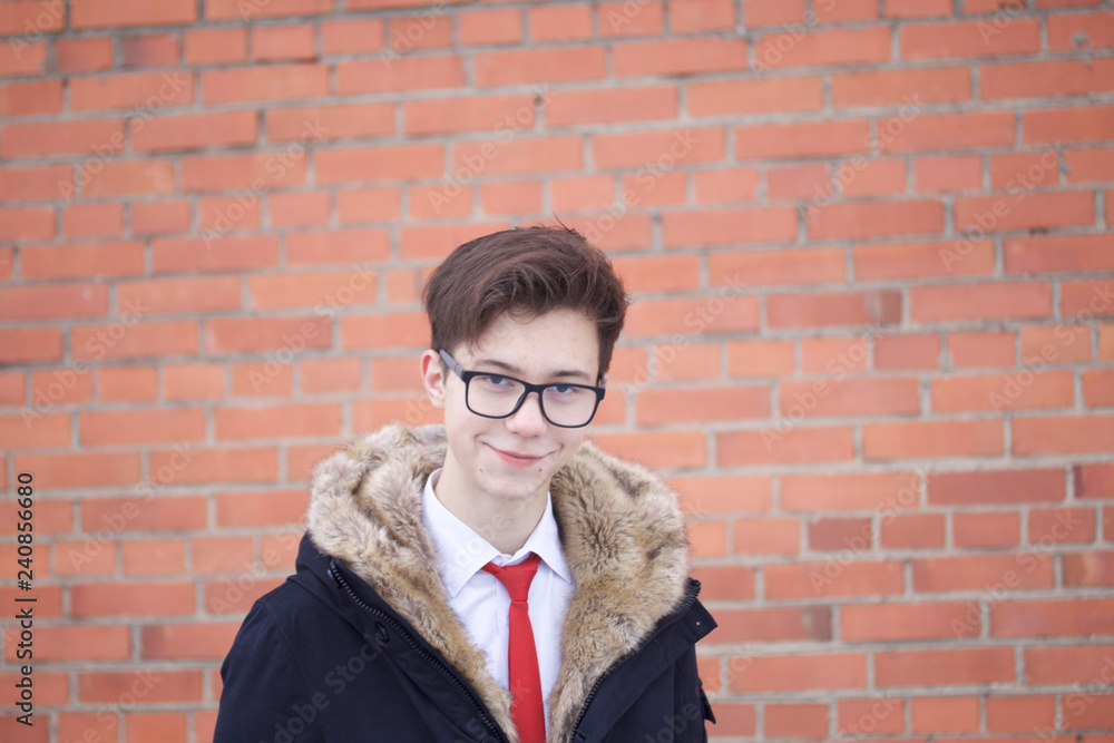 Portrait of a young man in a coat with a fur collar. On the background of a brick wall. Portrait of a young man in a coat with a fur collar. On the background of a brick wall.