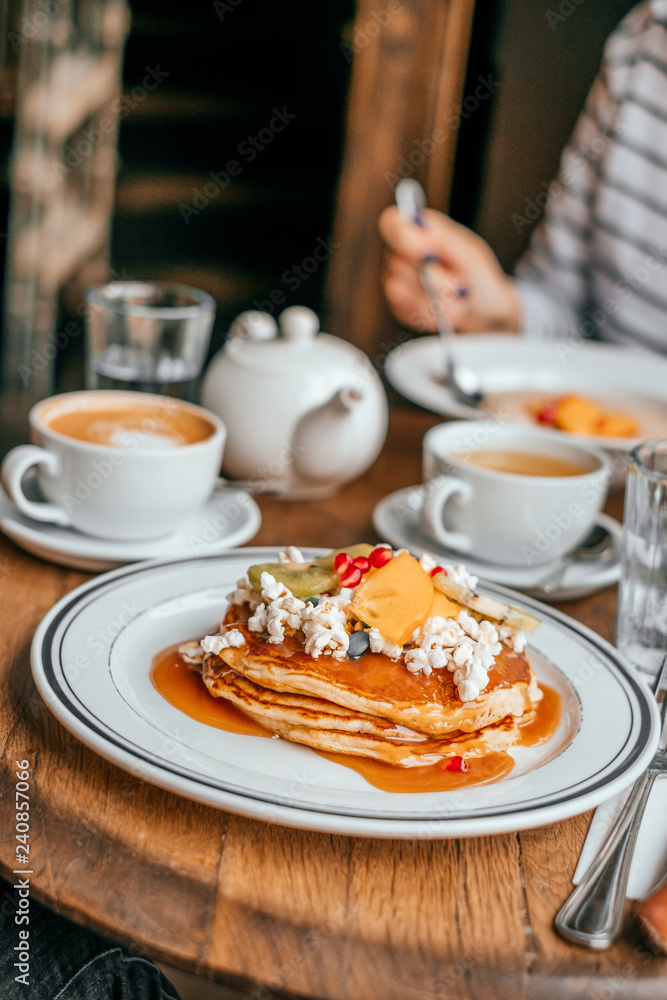 Perfect breakfast in the city cafe with pankakes, oatmeal, coffe and tea on the round wooden table. Perfect breakfast in the city cafe with pankakes, oatmeal, coffe and tea on the round wooden table.