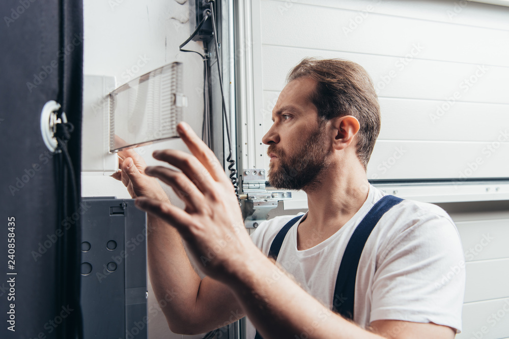 Fototapeta premium concentrated male bearded handyman checking electrical box