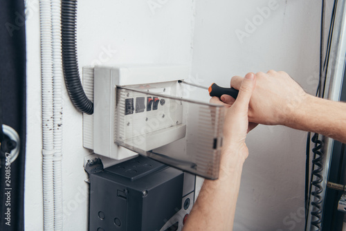 cropped image of male electrician repairing electrical box by screwdriver