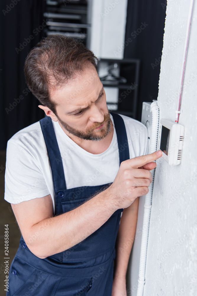 focused adult male handyman checking electrical panel focused adult male handyman checking electrical panel