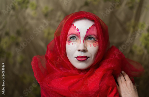 Mysterious mystical woman with a face painted white-red.