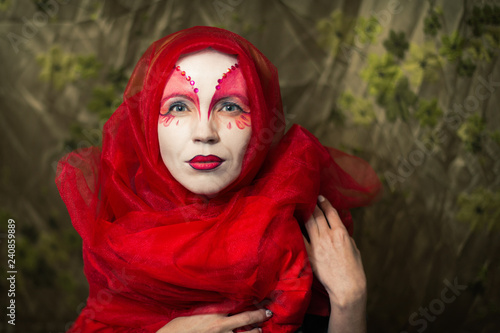 Mysterious mystical woman with a face painted white-red.