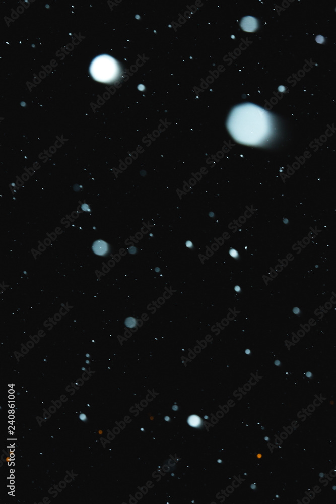 Flakes of snow falling on a black background. Isolated