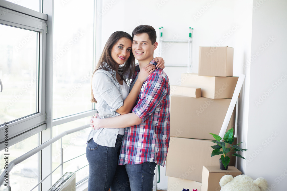 New Home. Funny young couple enjoy and celebrating moving to new home. Happy couple at empty room of new home New Home. Funny young couple enjoy and celebrating moving to new home. Happy couple at empty room of new home