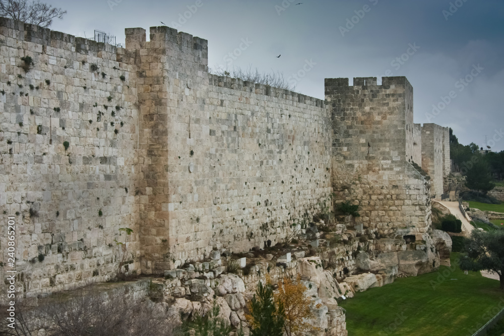 Medieval walls of Jerusalem. Ancient stone, gloomy sky.