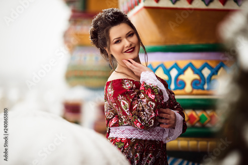 Beautiful woman is wearing traditional russian clothes in winter park full of snow photo