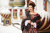 Beautiful happy woman is wearing traditional russian clothes in winter park
