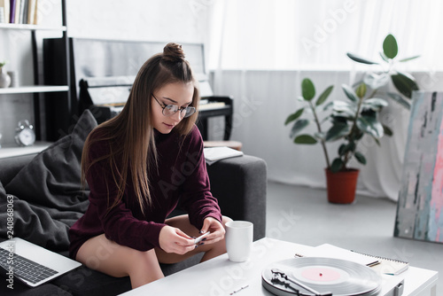 Canvas Print girl sitting at table and rolling marijuana joint in living room