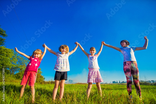 Large group of kids running in summer field with sky background