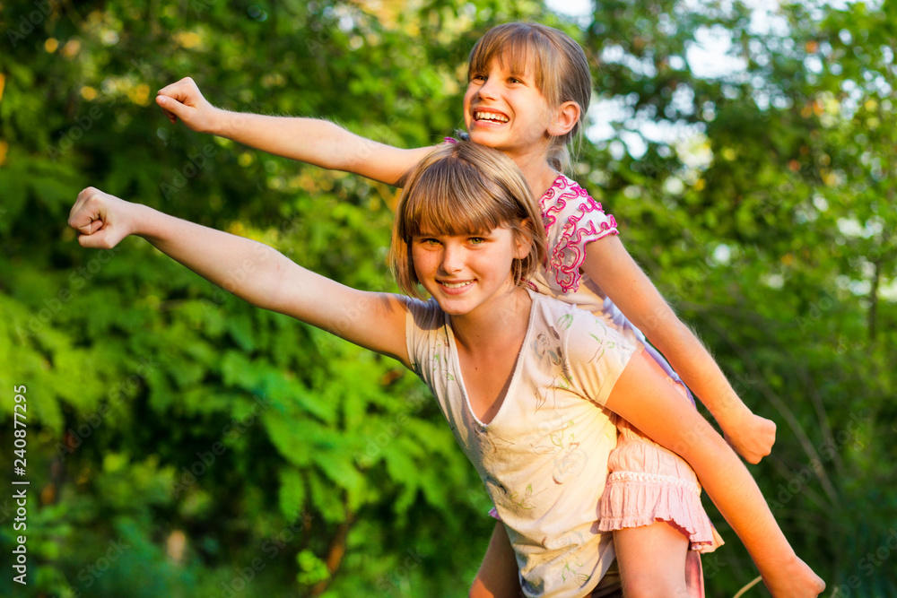 Fototapeta premium Two child girls playing together. Sisters play Superhero. Happy kids having fun, smiling and hugging. Family holiday and togetherness.