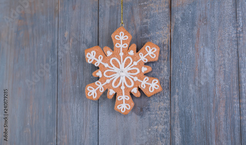 Gingerbread snowflakes cookies for Christmas hanging on wooden background.