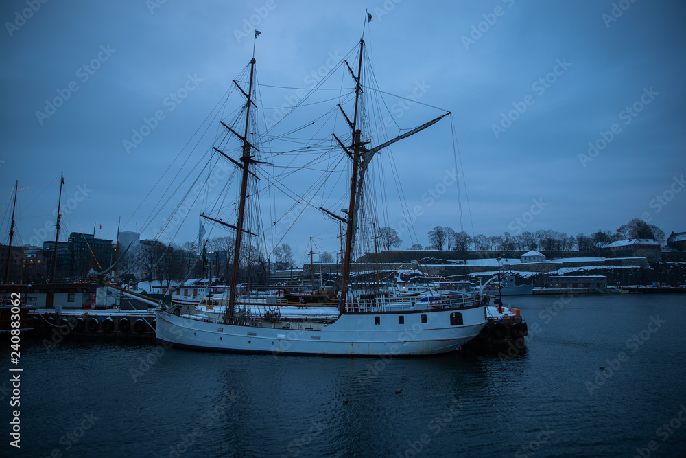 Port in Oslo Norway during sunset in winter. View to the sea and anchored ships.