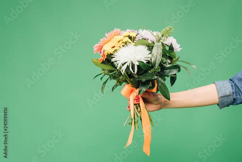 Vászonkép cropped view of woman holding flower bouquet isolated on green
