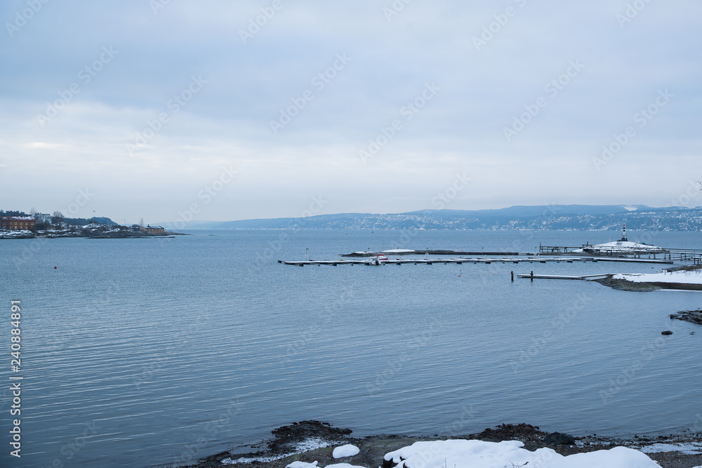 A pier for boats traveling between the Islands around Oslo Norway during the winter overlooking the sea and the Fjord