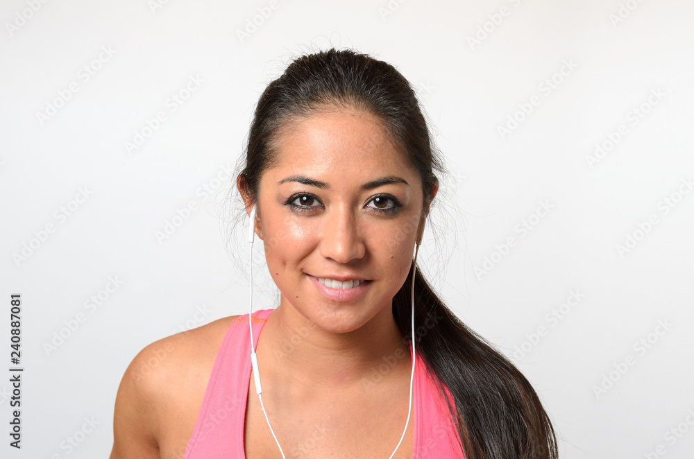 Pretty woman in pink top with earbuds on white Pretty woman in pink top with earbuds on white