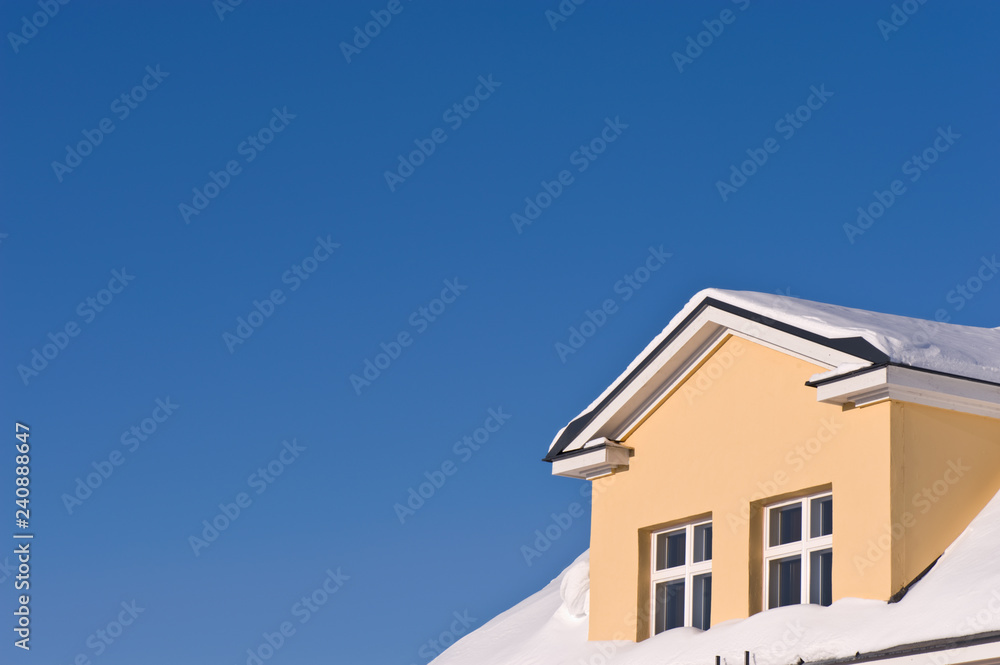 Detail of house exterior against blue sky.