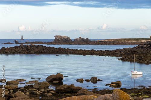 Porspoder, France. Rocky landscape in the coast of Brittany (Bretagne) at dawn on a beautiful summer day, with a boat and a lighthouse photo