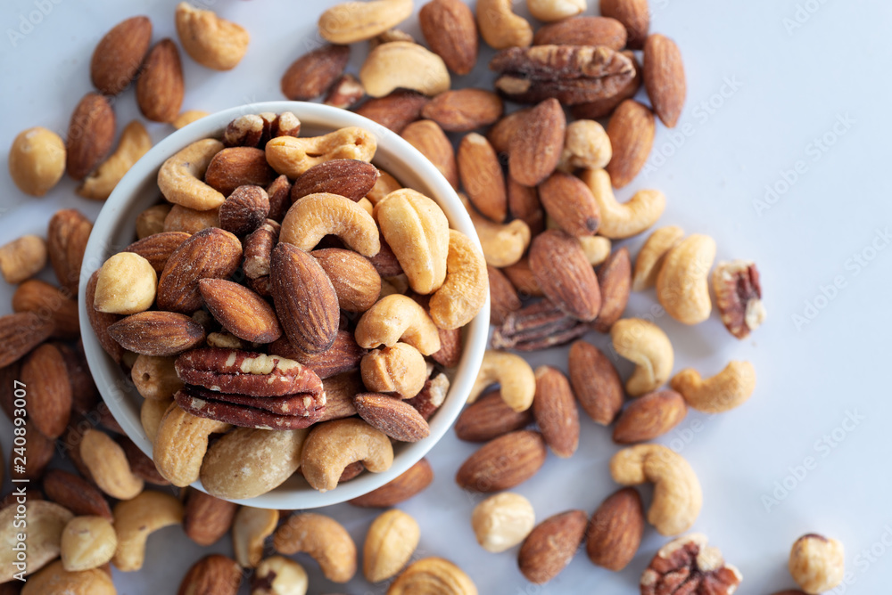 roasted mixed nuts in white ceramic bowl on barble table background. roasted mixed nuts in white ceramic bowl on barble table background.