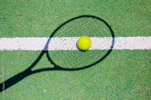 Tennis ball and shadow from racket on a green tennis hard court