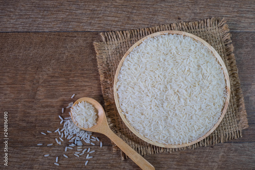 White rice, Rice grian, in bowl wooden and sack with spoon wooden on the rustic wooden background, top view. photo