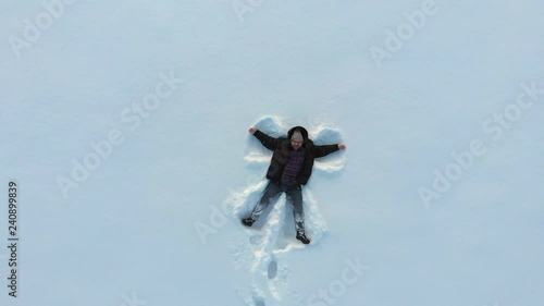 Wallpaper Mural Top aerial view of happy smiling man making snow angel figure by arms and lying in snow, copy space. Winter outdoor activity concept Torontodigital.ca