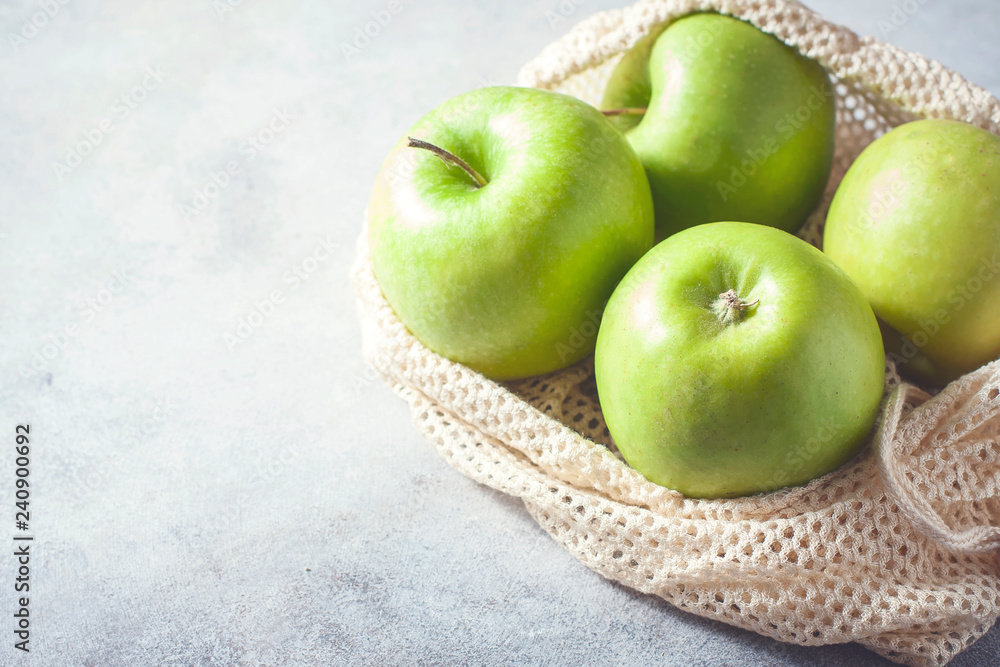 Organic green apples in reusable cotton net bag on wooden table. Eco-package, zero waste concept. Organic green apples in reusable cotton net bag on wooden table. Eco-package, zero waste concept.