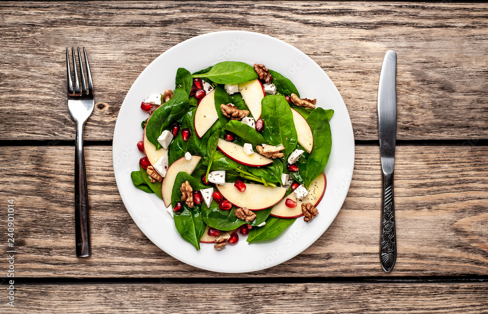spinach salad, apple, pomegranate, cheese, walnut salad on wooden steel spinach salad, apple, pomegranate, cheese, walnut salad on wooden steel