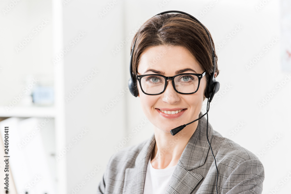 smiling beautiful call center operator in glasses and headset looking at camera in office smiling beautiful call center operator in glasses and headset looking at camera in office