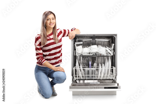 Quadro su tela Beautiful young woman kneeling next to an open dishwasher