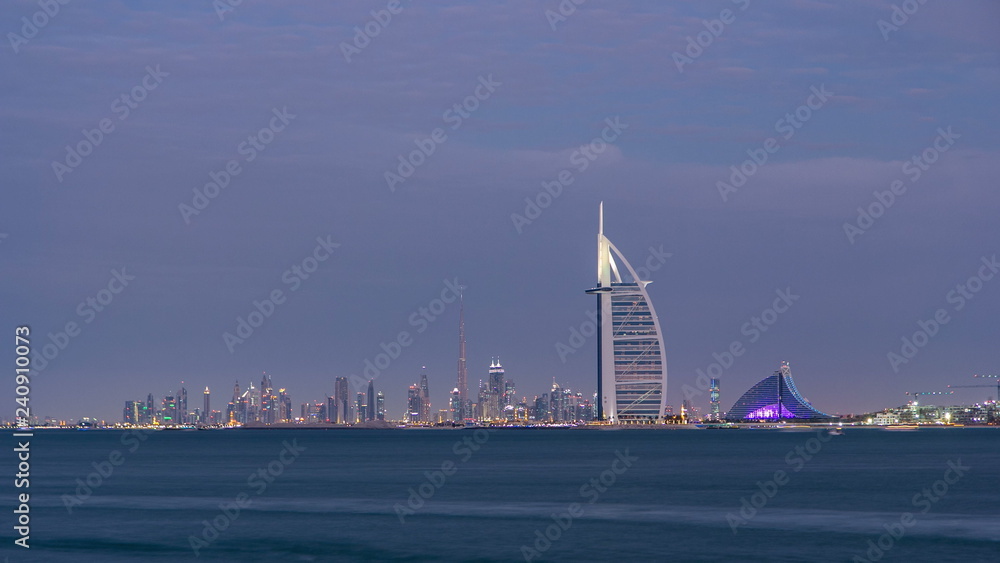 Dubai skyline with Burj Al Arab hotel during sunset and day to night timelapse.