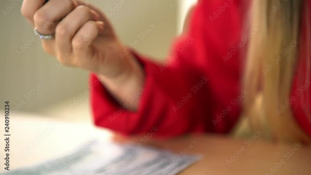 Luscious blonde in a red jacket performs office work, an office girl with big forms counts money on a calculator, counts bills, persuades a client to buy a product or service Luscious blonde in a red jacket performs office work, an office girl with big forms counts money on a calculator, counts bills, persuades a client to buy a product or service