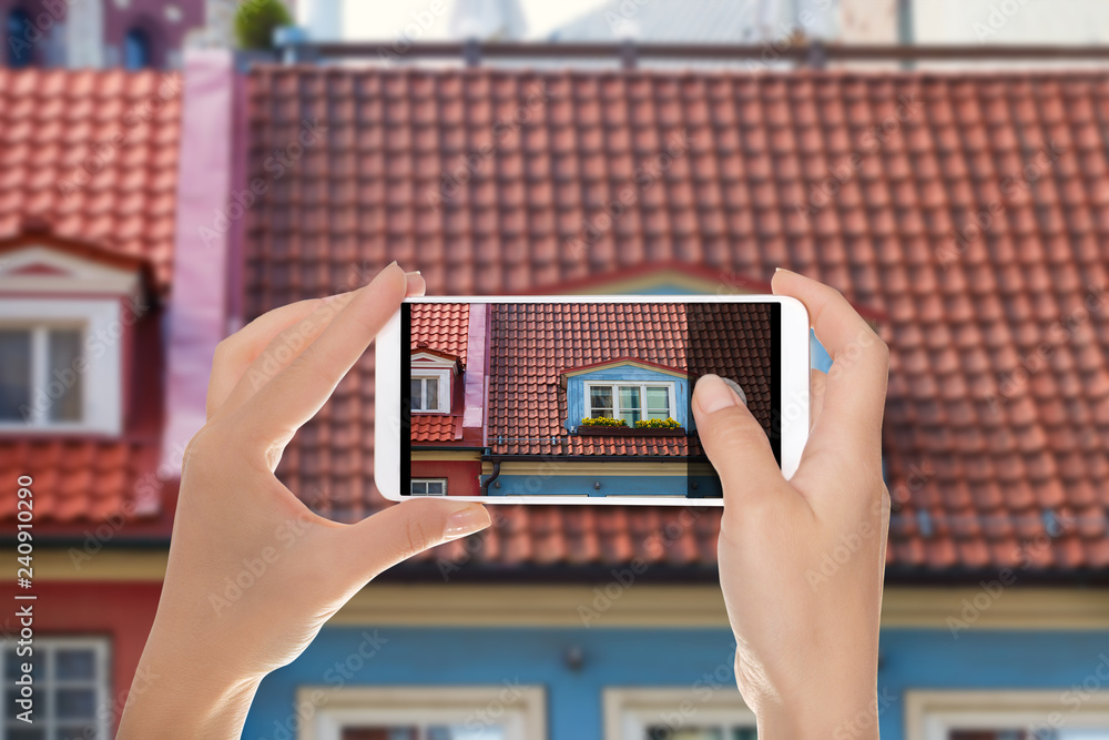 Φωτογραφία A man is making a photo of window with flowers in the roof of an old house in th