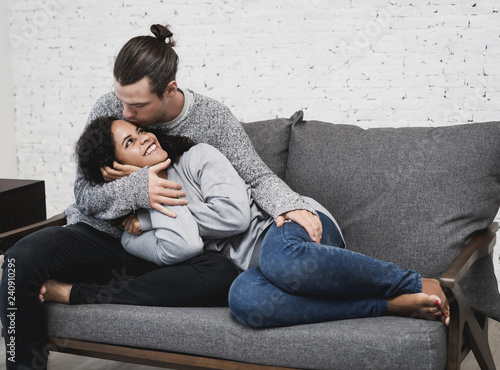 Canvastavla Sweet couple wearing sweater and cuddleling while lying down on the sofa in the living room at home