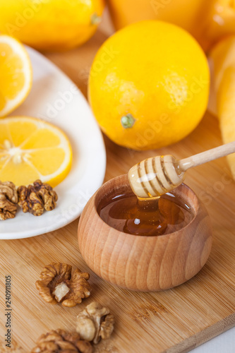 honey in a wooden bowl with honey dipper and lemon on a wooden kitchen board
