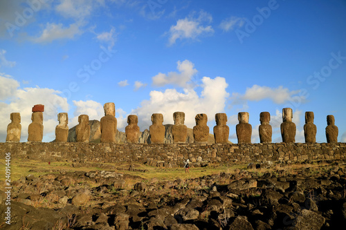 One female tourist taking photos at the back of 15 gigantic Moai statues of Ahu Tongariki in the morning sunlight, Easter Island, Chile 