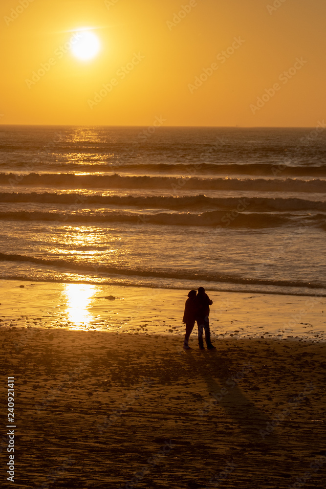 Silhouette of a couple taking a selfie against the sunset over the Atlantic Ocean