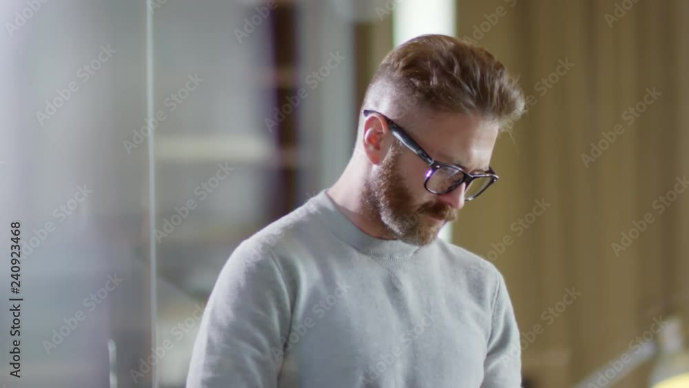 Medium shot of concentrated bearded man in glasses using tablet computer or smartphone application Medium shot of concentrated bearded man in glasses using tablet computer or smartphone application