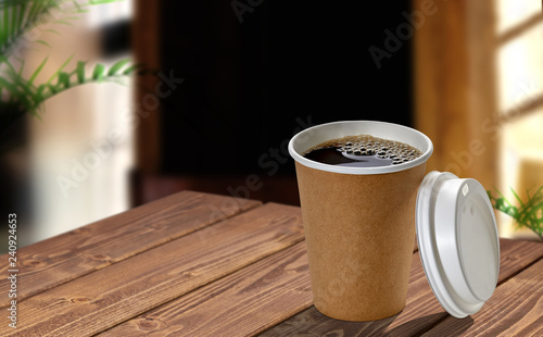Disposable paper cup of coffee to go on wooden table at cafe. 