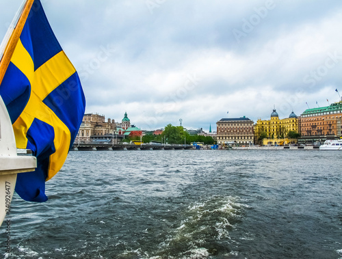 Panoramic view from the excursion boat with the flag of Sweden on the beautiful buildings of Stromkajen in the center of Stockholm Sweden