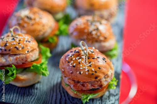 Tasty homemade mini-hamburgers on wooden board close