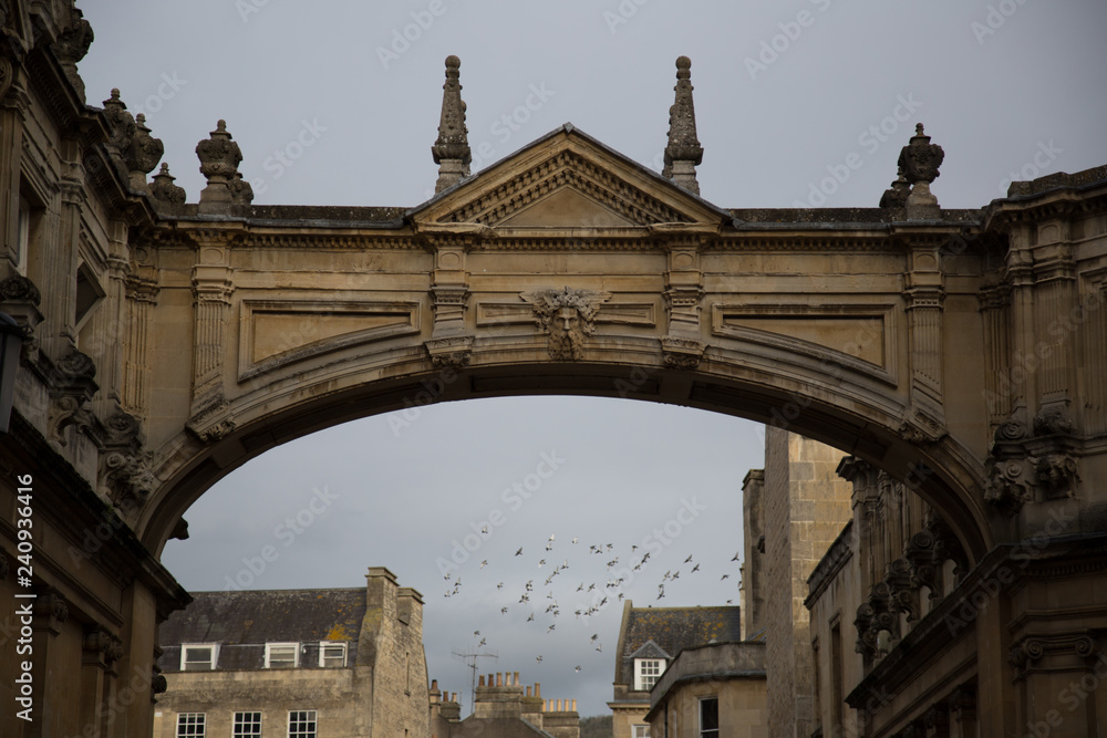 Arch over a English street with flock of birds in the sky