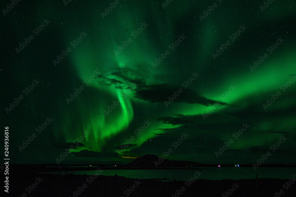 Winter scenic landscape night view of  Aurora Borealis/Northern lights dancing on the clear sky full of stars above lake Myvatn, north Iceland Beautiful winter wonderland/fairytale background scene. 