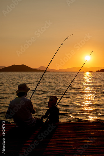 Seaside or beach fishing man and kid at sunset
