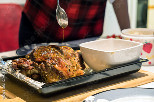 A roast leg of lamb on baking tray on christmas table