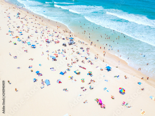 An aerial view of people on the beach with blue water on hot summer's day © Darren