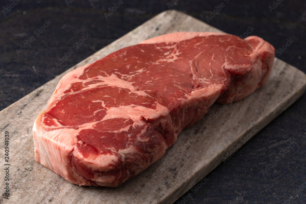 Raw New York Strip Steak on a Dark Slate Surface