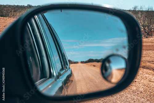 The endless roads of the outback, the Australian desert, seen through the mirror of a car.