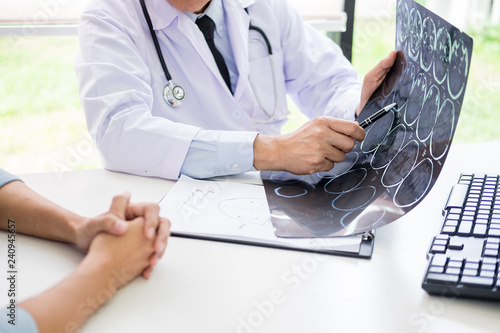 doctor analyzing a scan or x-ray film or explains a CT scan thoughtful expressions method talking to patient treatment on brain to an anomaly. photo