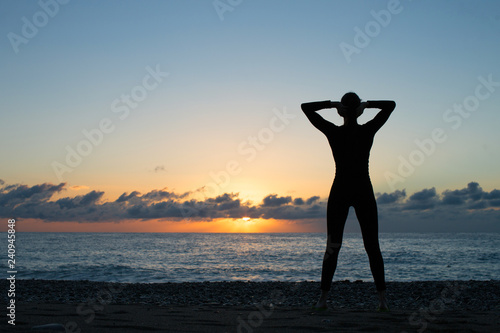 Human silhouette standing on the sea shore and looking at the setting sun